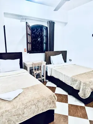 two beds in a room with a checkered floor at Golden Rose Guesthouse in Luxor