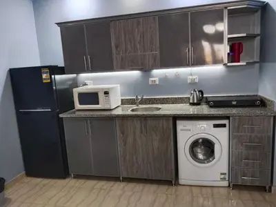 a kitchen with a washing machine and a microwave at Andalus in in Hurghada