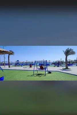 a playground with swings and a tree in a park at Adler-Hurghada Holiday apartment sea view rooftop pool 80m to beach in Hurghada