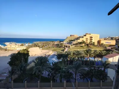a view of a resort with palm trees and the ocean at Adler-Hurghada Holiday apartment sea view rooftop pool 80m to beach in Hurghada