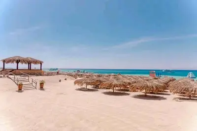 a beach with some straw umbrellas and the ocean at Contesa Do in Hurghada
