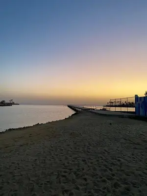 a beach with a pier and the ocean at sunset at Scandic resort private beach in Hurghada