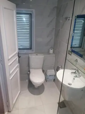 a white bathroom with a toilet and a sink at Jamaica Dream in Luxor