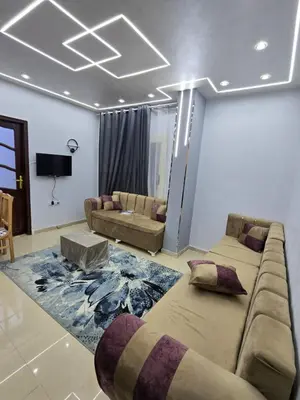 a living room with a large couch and a living room with a tv at Larose Apartment in Hurghada