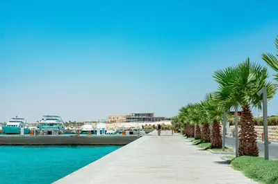 a pathway with palm trees next to a marina at The Kaktus Somabay in Hurghada