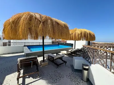 a resort with a swimming pool and a straw umbrella at Arаbian Suites by Imperial in Hurghada