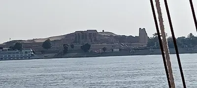 a castle on a hill next to a body of water at Sunset and Sand Felucca Life on the Nile in Jazīrat Aswān