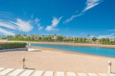 a swimming pool on a beach with palm trees at Serene Lakeview Escape 2BR at Cyan ElGouna in Hurghada
