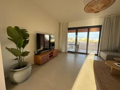 a living room with a television and a potted plant at Kamaran El Gouna - 1 bed ground in Hurghada