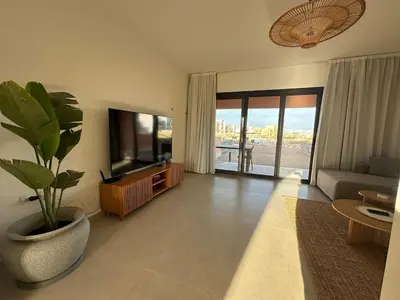 a living room with a television and a potted plant at Kamaran El Gouna - 1 bed ground in Hurghada