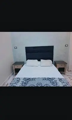 a bedroom with a large bed with two night tables at Nile palace apartment in Luxor