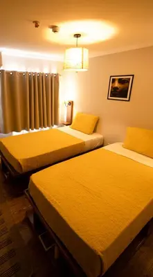 two beds in a hotel room with yellow sheets at Escaleeh Dahabiya Tranquil sailing in Jazīrat Suhayl