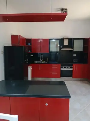 a kitchen with red cabinets and a black counter top at Villa yulla in Hurghada