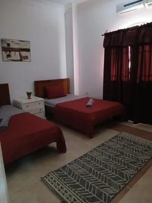 a bedroom with two beds and a rug at Cozy Villa in Hurghada