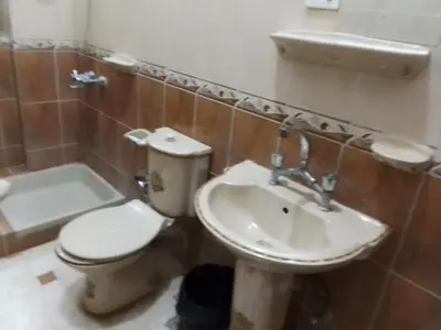 a bathroom with a toilet and a sink at Ziggy Marley Backpackers Hostel in Al Aqālitah