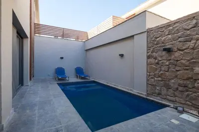 a swimming pool with two blue chairs next to a building at Luxury 2BR Bali • Heated Pool in Hurghada