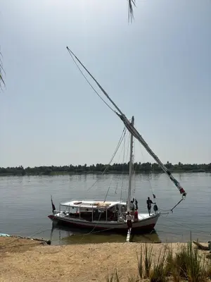 a boat sitting on the water next to a beach at Isis Nubian Services in Jazīrat Aswān