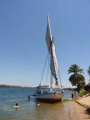 a sail boat in the water on a beach at Isis Nubian Services in Jazīrat Aswān