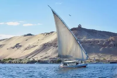 a small boat with a sail on the water at Isis Nubian Services in Jazīrat Aswān