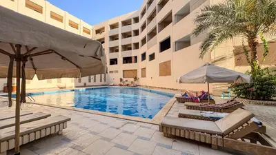 a swimming pool with chairs and umbrellas next to a building at Elite AlDaU Heights in Hurghada