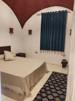 a bedroom with a large bed with blue curtains at Nature House in Luxor
