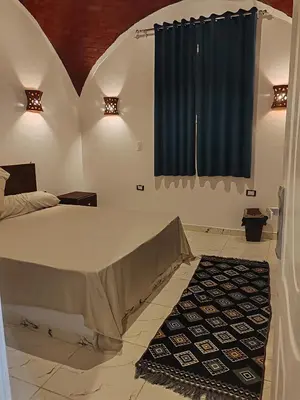 a bedroom with a bed and a blue window at Nature House in Luxor