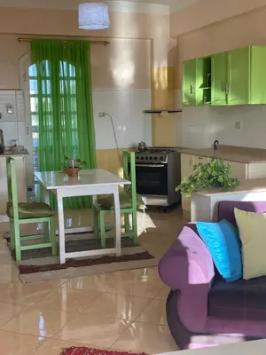 a kitchen with a white table and green cabinets at Roses House Ladies & families only in Luxor