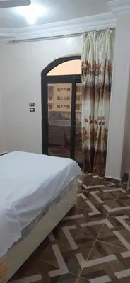 a bedroom with a bed and a room with a window at Sphinx Avenue street in Luxor
