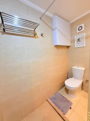 a bathroom with a toilet and a tile wall at Hotel Apartment 1 very nice and quiet hurghada in Hurghada