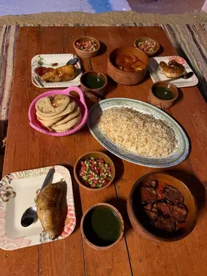 a wooden table topped with different types of food at Heissa Nubian Hostel in Aswân Reservoir Colony