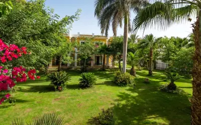 a house with palm trees and flowers in a yard at Lilyland Beach Resort & Waterpark in Hurghada