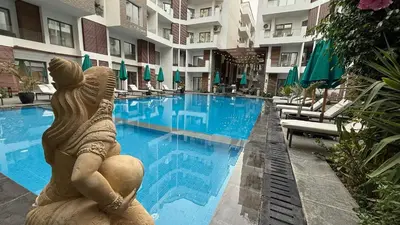 a statue of a mermaid sitting next to a swimming pool at Imperial Resort Hurghada in Hurghada