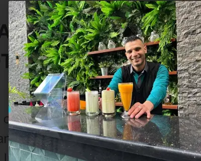 a man sitting at a counter with a table with drinks at Imperial Resort Hurghada in Hurghada