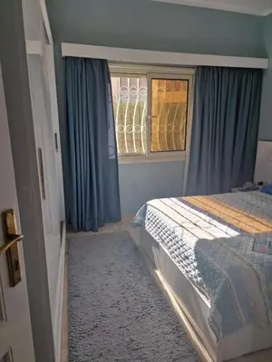 a bedroom with a bed with blue curtains and a window at Apartment for rent 2 bed rooms in Hurghada