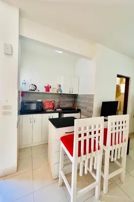 a kitchen with white cabinets and a red table and chairs at Inviting 1-Bed Apartment in Hurgada in Hurghada