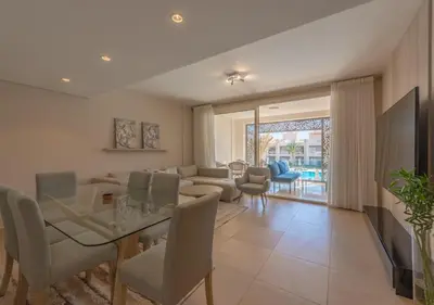 a living room with a table and chairs and a couch at Sea View 2BR Mangroovy Gouna I Swimming Pool and Red Sea Beach in Hurghada