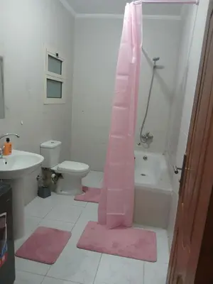 a bathroom with a pink shower curtain and a toilet at Cozy Apartment in Hurghada