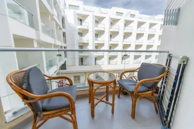 a balcony with chairs and a table and a building at Scandic Resort Hurghada مبني سكندك رزوت الغردقة in Hurghada
