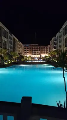 a large swimming pool in front of a building at night at Fanadir Bay apartment in Hurghada