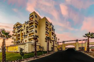 a large building with palm trees in front of it at Studio in Dow Heights Compound in Hurghada
