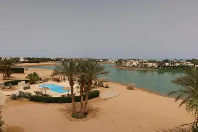 a view of a beach with palm trees and a body of water at Spacious 1bd on the Beach - White Villas, El Gouna in Hurghada