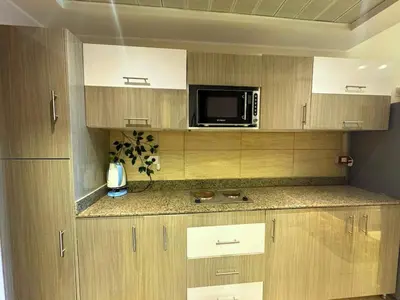 a kitchen with wooden cabinets and a microwave at More Relaxation Aldau Heights Studio in Hurghada in Hurghada