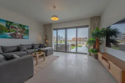 a living room with a couch and a large window at Chic 1 BR with private jacuzzi in Banī Ghālib