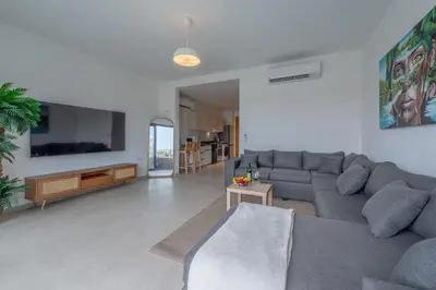 a living room with a couch and a tv at Chic 1 BR with private jacuzzi in Banī Ghālib