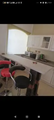 a kitchen with a white counter and a red chair at Luxor Egypt in Al Baghdādī