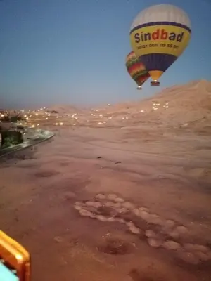 two hot air balloons are flying over a field at House of peace in Al Aqālitah