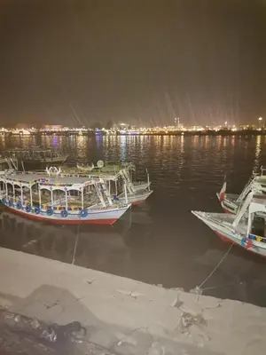 three boats are docked in the water at night at House of peace in Al Aqālitah