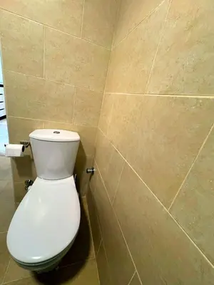 a bathroom with a white toilet in a tiled wall at Diamond Aldau in Hurghada