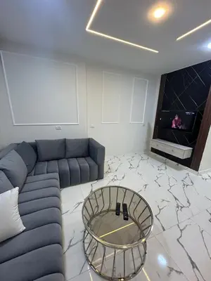 a living room with a blue couch and a glass table at Two Bedroom Apartment in Hurghada