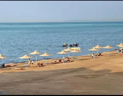 a beach with umbrellas and people riding horses at Modern 2 Bedroom Apartment with Private Beach Hurghada in Hurghada